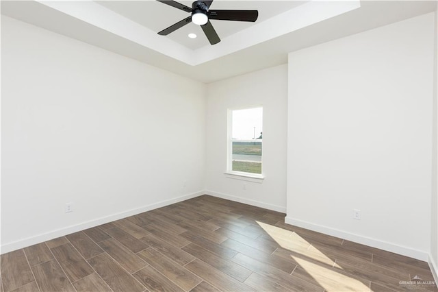 spare room with dark wood-style floors, recessed lighting, a raised ceiling, a ceiling fan, and baseboards