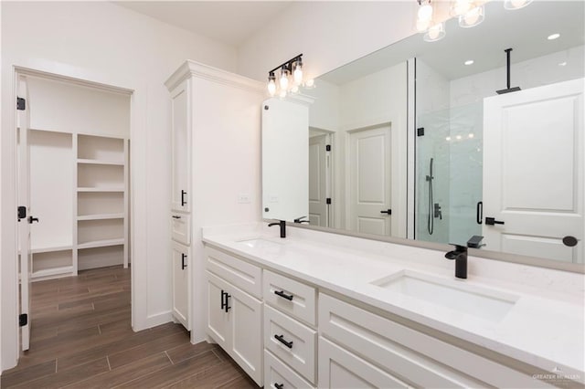 bathroom with double vanity, a stall shower, a sink, and wood tiled floor