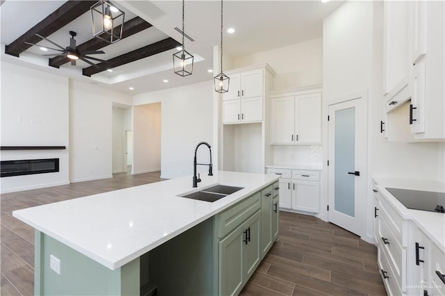 kitchen featuring a ceiling fan, a glass covered fireplace, wood finish floors, white cabinetry, and a sink