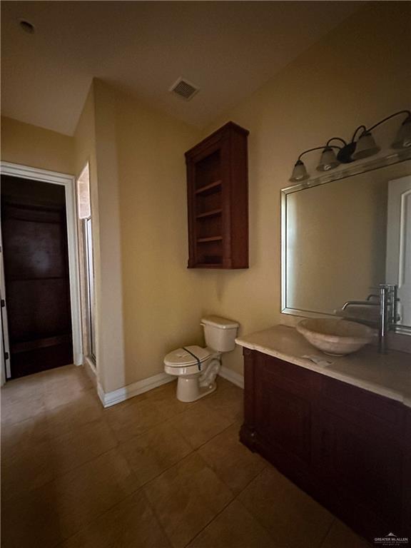 bathroom featuring tile patterned floors, vanity, toilet, and walk in shower