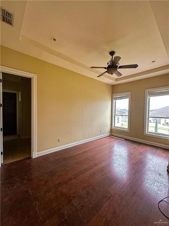 spare room with hardwood / wood-style floors, ceiling fan, and a raised ceiling