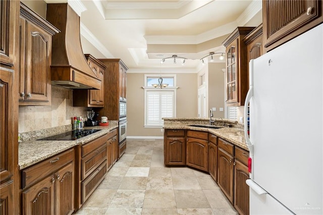 kitchen featuring premium range hood, sink, a raised ceiling, white fridge, and black electric stovetop