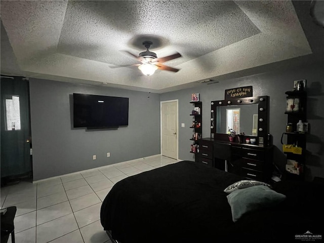 tiled bedroom featuring multiple windows, a textured ceiling, a raised ceiling, and ceiling fan