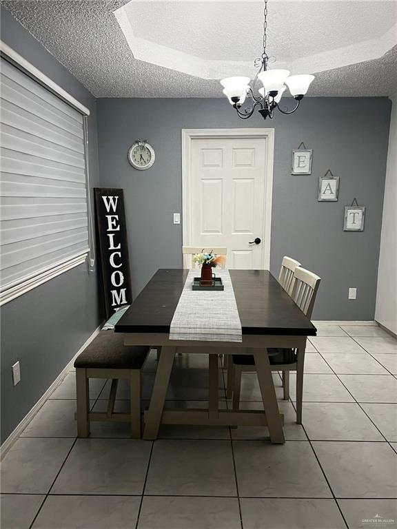 tiled dining space with a textured ceiling and a notable chandelier