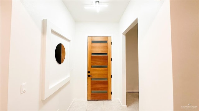 corridor with light tile patterned floors and baseboards