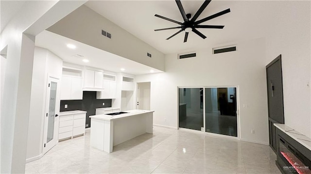 kitchen with white cabinets, a kitchen island, visible vents, and ceiling fan