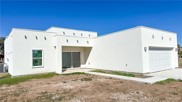 back of property featuring a garage and stucco siding