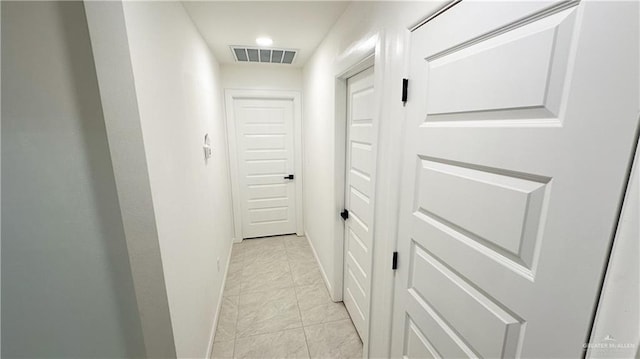 hallway with baseboards and visible vents