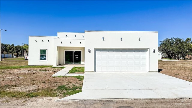 view of front of property featuring a garage, concrete driveway, and stucco siding