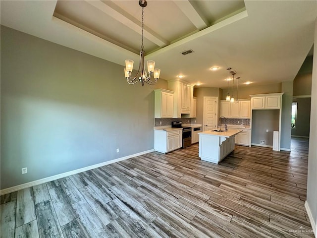 5016 Kendlewood Ave, Mcallen, TX 78501 - kitchen with stainless steel range with electric cooktop, a sink, a chandelier, an island with sink, and white cabinetry