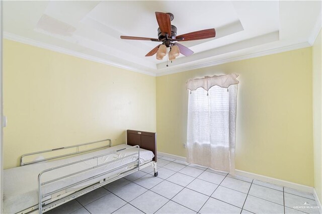 bedroom featuring a ceiling fan, crown molding, light tile patterned floors, a tray ceiling, and baseboards