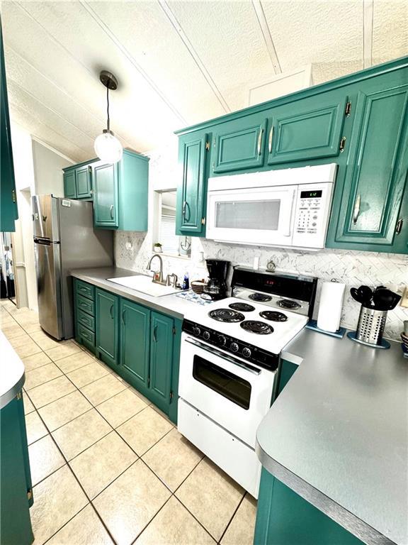 379 Sand Dollar Dr, Port Isabel, TX 78578 - kitchen with white appliances, light tile patterned flooring, backsplash, a textured ceiling, and green cabinetry