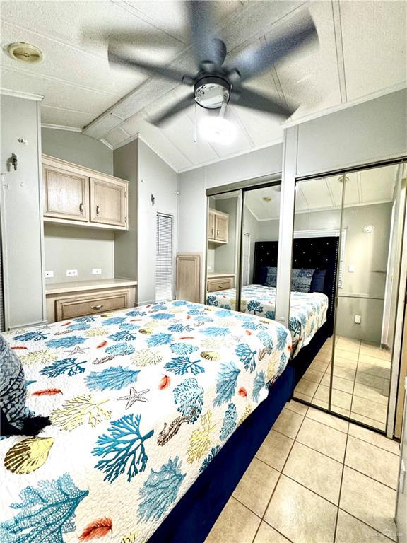 379 Sand Dollar Dr, Port Isabel, TX 78578 - bedroom with light tile patterned flooring, multiple closets, vaulted ceiling, and a ceiling fan