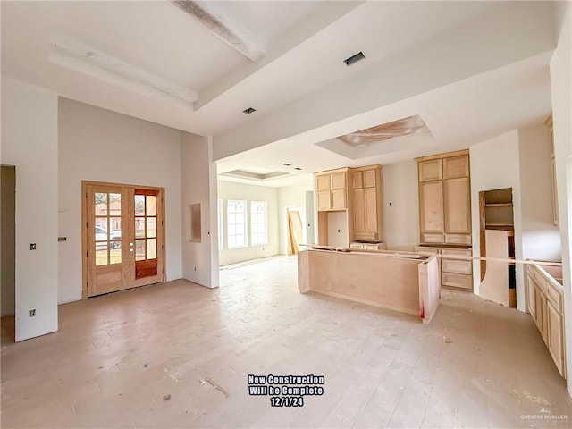 kitchen featuring french doors, light brown cabinets, a raised ceiling, and a kitchen island