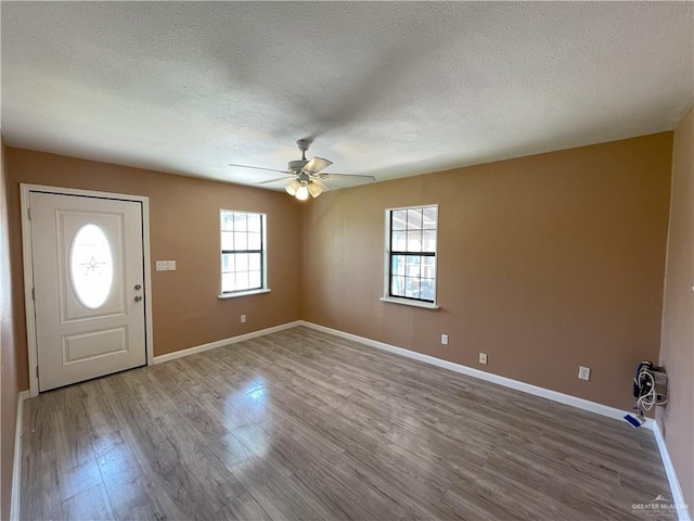 foyer with a textured ceiling, wood finished floors, ceiling fan, and baseboards