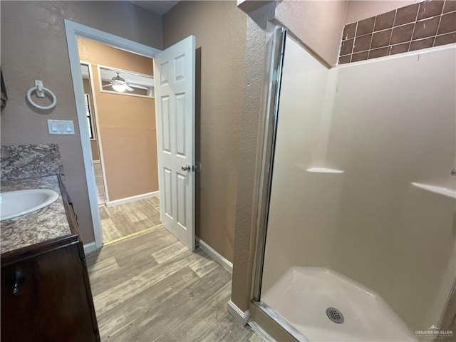 bathroom with a shower stall, ceiling fan, a textured wall, wood finished floors, and vanity