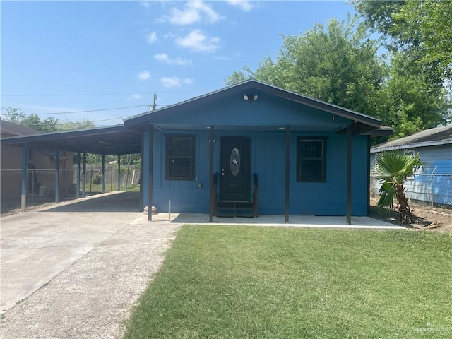 view of front facade with driveway, fence, an attached carport, and a front lawn