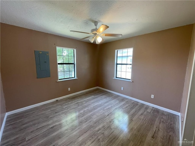 unfurnished room featuring wood finished floors, a healthy amount of sunlight, electric panel, and ceiling fan
