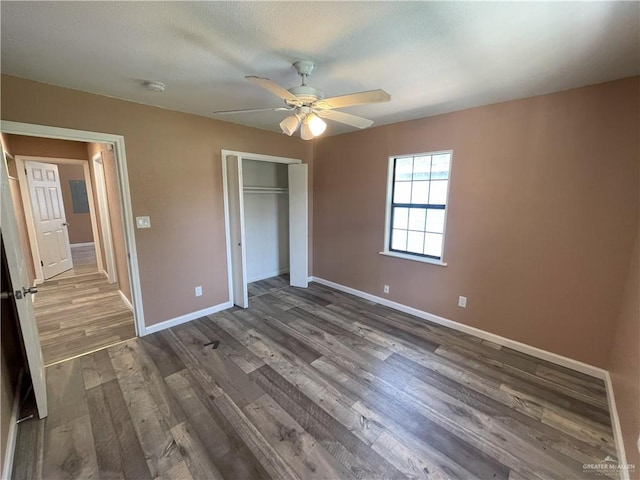 unfurnished bedroom featuring a closet, dark wood finished floors, and baseboards