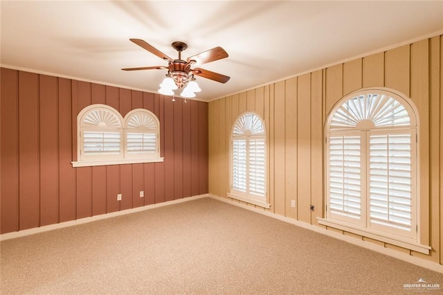 empty room with crown molding, ceiling fan, and carpet