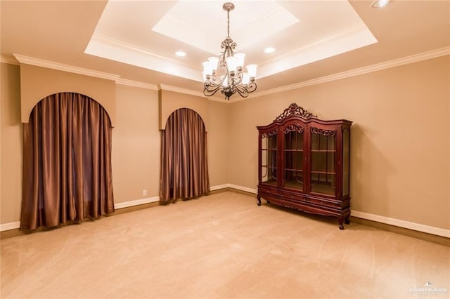 unfurnished room featuring a raised ceiling, ornamental molding, carpet flooring, and a notable chandelier