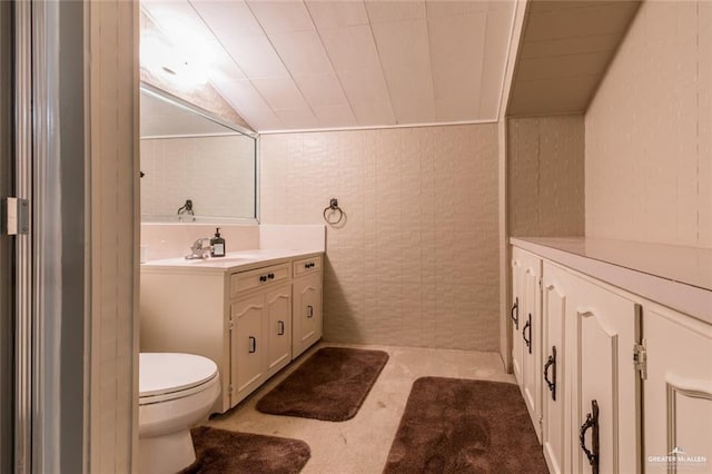 bathroom with vanity, vaulted ceiling, tile walls, and toilet