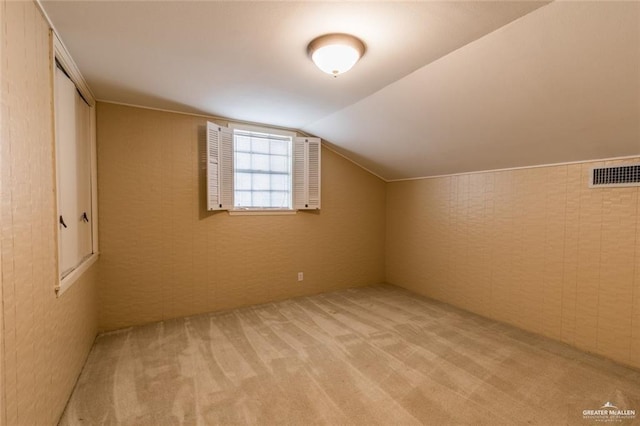 additional living space featuring lofted ceiling and light carpet