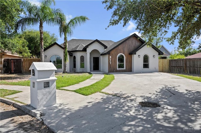 view of front facade with driveway, fence private yard, and stucco siding