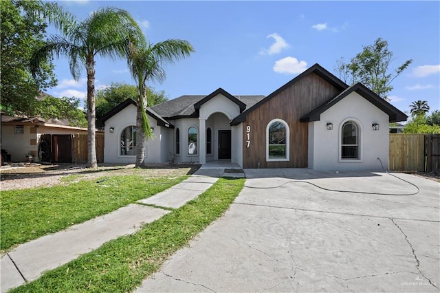 ranch-style house with a front lawn, stucco siding, and fence