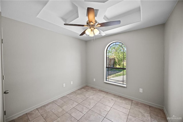empty room with baseboards, a ceiling fan, and a raised ceiling