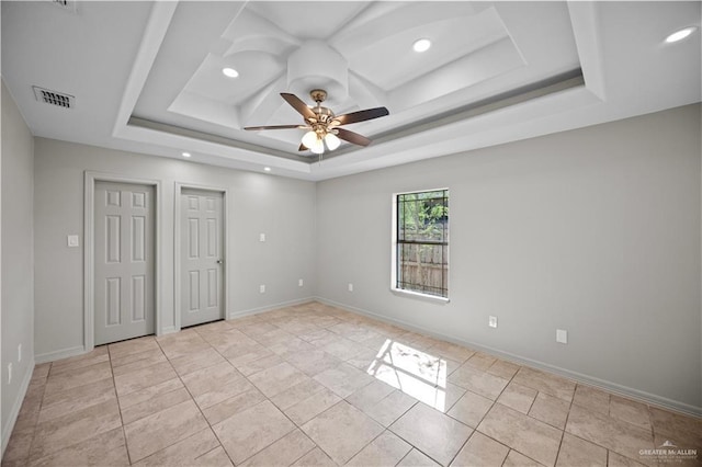 empty room featuring a raised ceiling, a ceiling fan, recessed lighting, and visible vents