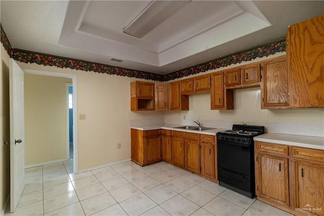 kitchen with a tray ceiling, black stove, light tile patterned floors, and sink