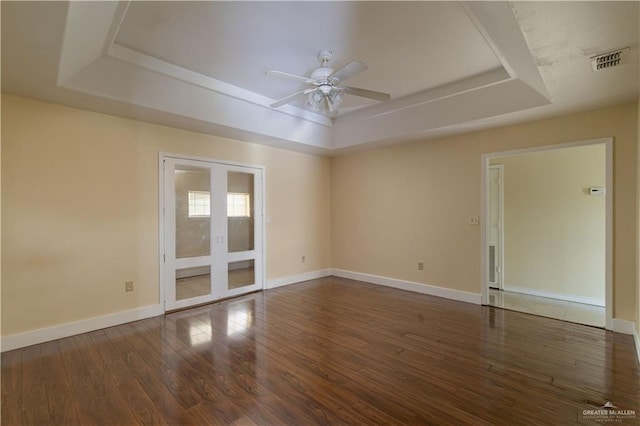 empty room featuring a raised ceiling, dark hardwood / wood-style flooring, and french doors