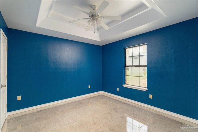 spare room with a tray ceiling and ceiling fan