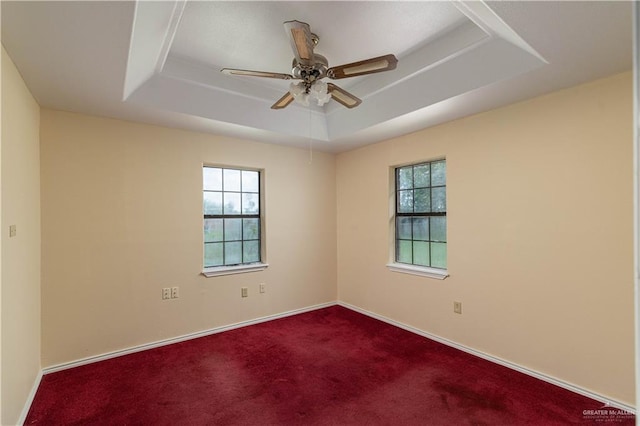 carpeted spare room featuring a tray ceiling and ceiling fan