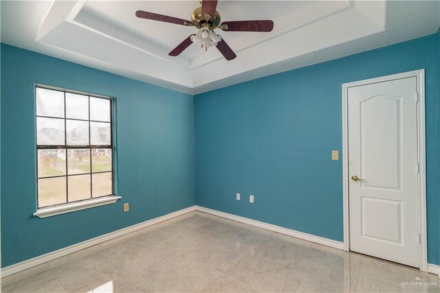 spare room with ceiling fan and a tray ceiling