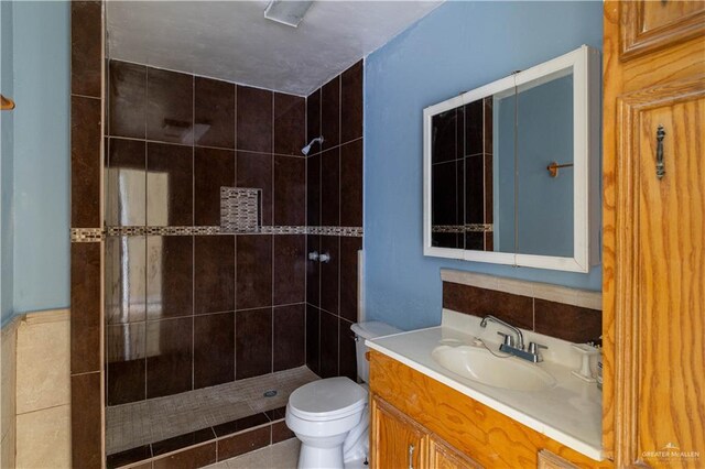 bathroom with vanity, toilet, and tiled shower