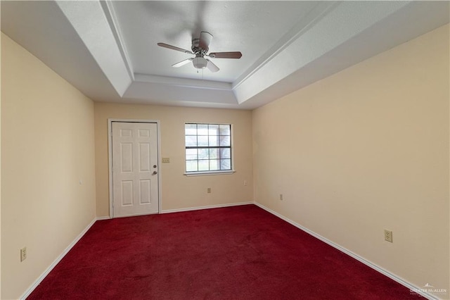 unfurnished room featuring carpet flooring, a tray ceiling, and ceiling fan