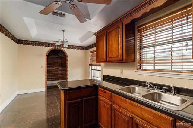 kitchen featuring kitchen peninsula, ceiling fan with notable chandelier, a tray ceiling, and sink