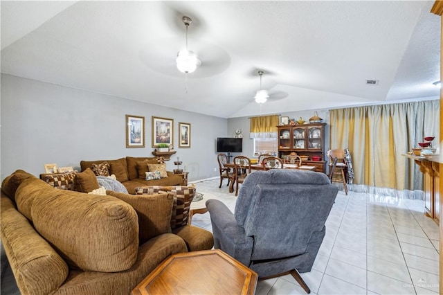 living area with lofted ceiling, ceiling fan, and light tile patterned floors
