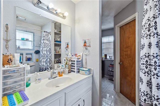 bathroom featuring healthy amount of natural light, tile patterned flooring, a textured wall, vanity, and curtained shower