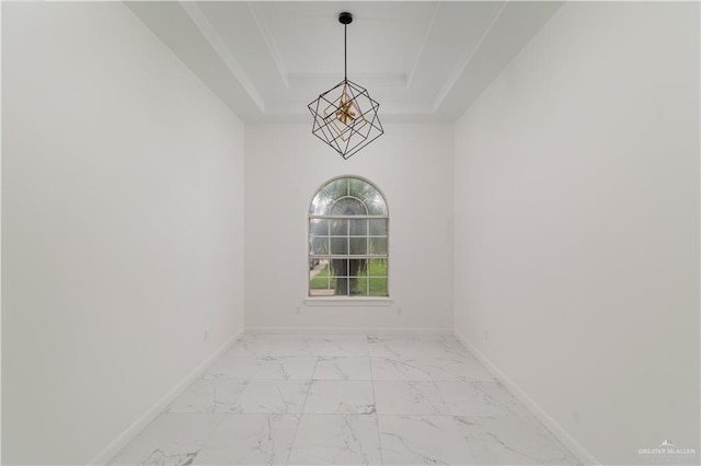 empty room featuring a notable chandelier and a raised ceiling