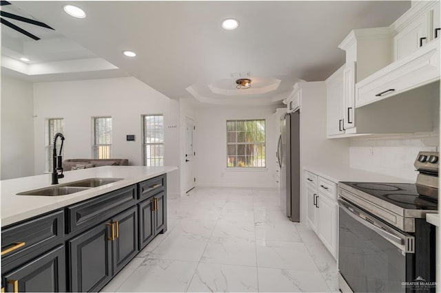 kitchen with white cabinetry, sink, ceiling fan, a tray ceiling, and appliances with stainless steel finishes