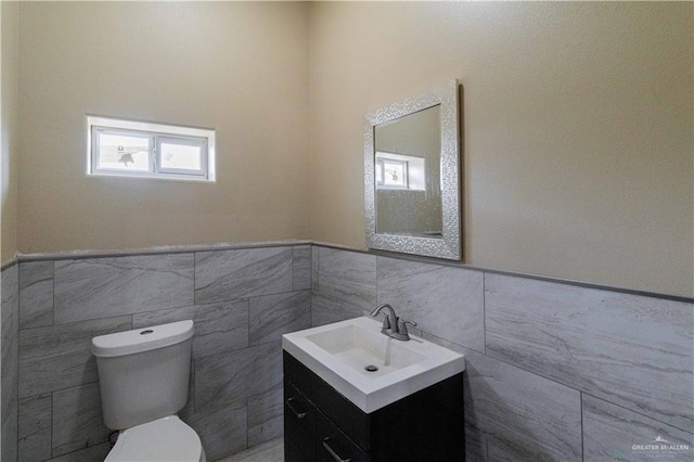 bathroom featuring vanity, toilet, and tile walls