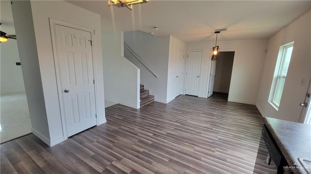 unfurnished living room featuring dark wood-type flooring and ceiling fan