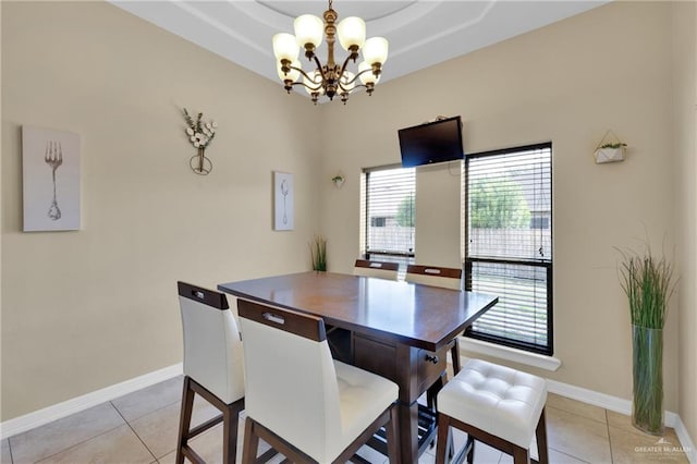 tiled dining room featuring a tray ceiling and a chandelier