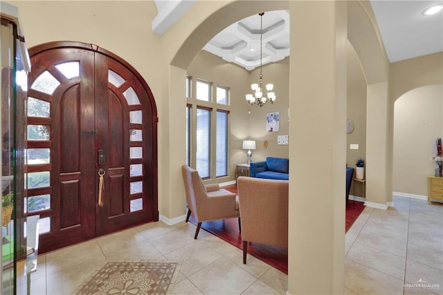 entrance foyer featuring light tile patterned flooring, beamed ceiling, a chandelier, a high ceiling, and coffered ceiling