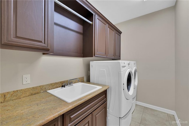 laundry area featuring cabinets, washer and clothes dryer, sink, and light tile patterned floors