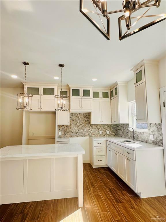 kitchen with sink, hanging light fixtures, dark hardwood / wood-style floors, a kitchen island, and white cabinetry