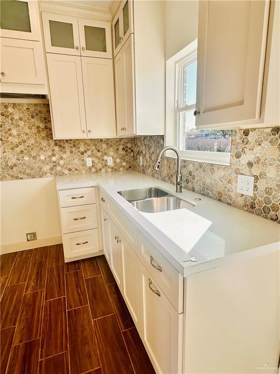 2110 Trinity, Donna, TX 78537 - kitchen with light countertops, glass insert cabinets, tasteful backsplash, white cabinets, and dark wood-type flooring